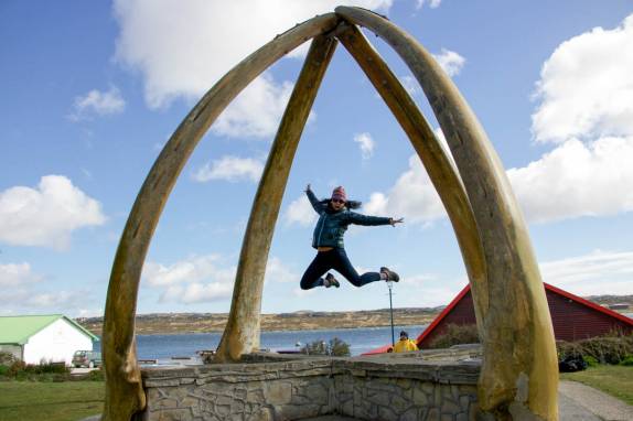 A Kim salta entre ossos de maxilar de uma baleia azul, em Port Stanley, capital de Falkland (foto de Jeff Orlowski)